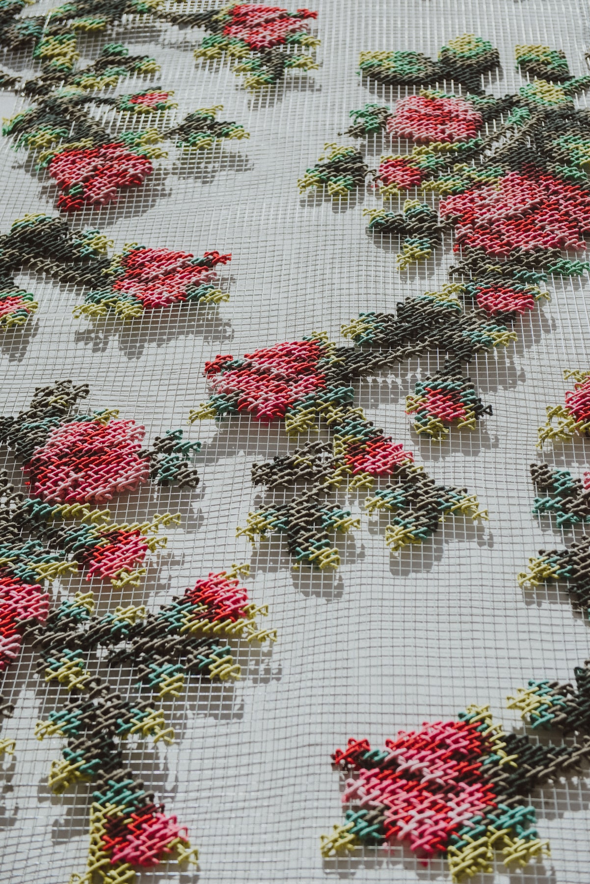 Flores — macro detail of embroidered roses on metallic mesh showing each stitch